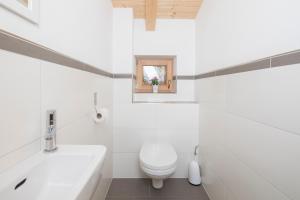 a white bathroom with a toilet and a sink at Bauernhaus Roßmoos in Alpbach