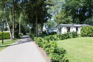 a walkway in front of a house with trees at TopParken – Recreatiepark de Wielerbaan in Wageningen