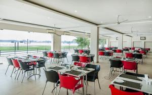 une salle à manger avec des tables, des chaises et des chaises rouges dans l'établissement Hotel Sonar Bangla Kolaghat, à Bāgnān