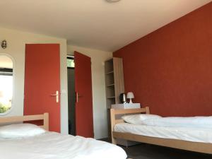 a bedroom with two beds and a red wall at camping Le Médiéval in Turckheim