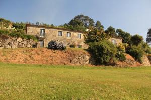 una gran casa de piedra en una colina con un campo en Quinta de Favaes, en Paredes de Coura