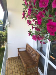 a wooden bench on a porch with pink flowers at Apartament u Gogoca in Tylicz