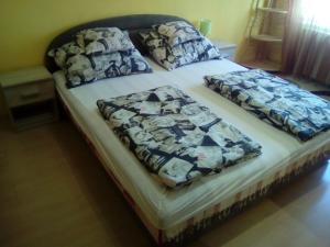 a bed with two pillows on top of it at Fészek Apartman in Békéscsaba