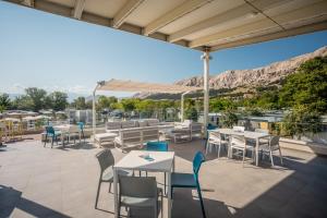 a patio with tables and chairs and a view at Valamar Camping Baška in Baška