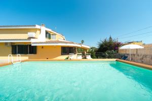 a villa with a swimming pool in front of a house at Villa Anbegia in Siracusa