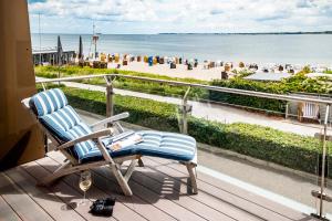 a rocking chair on a balcony with a view of the beach at Hotel Apartments Büngers - Mein Refugium am Meer mit Sommerstrandkorb in Strande