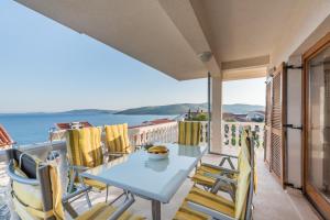 a balcony with a table and chairs and the ocean at Apartments Petrić in Seget Vranjica