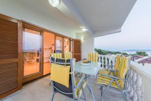 a balcony with a blue table and yellow chairs at Apartments Petrić in Seget Vranjica