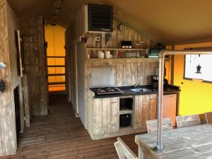 a kitchen with a stove and a sink in a room at Camping Ginsterveld in Burgh Haamstede