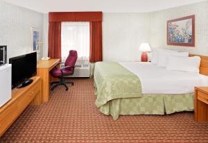 a hotel room with a bed and a desk and a television at Baymont by Wyndham St. Joseph/Stevensville in Stevensville