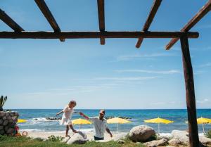 a man and woman playing on the beach at Baia Del Sole Resort in Capo Vaticano