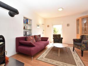 レリクにあるQuaint Apartment in Rerik near Seaのリビングルーム(紫色のソファ、椅子2脚付)