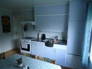a kitchen with white cabinets and a table and a sink at Peaceful Farm in Bøstad