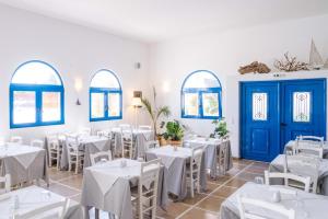 un ristorante con tavoli bianchi e porte e finestre blu di Lindos Sun Hotel a Líndos