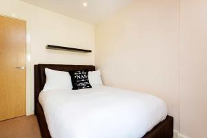 a bedroom with a white bed with a black pillow on it at Veeve - Contemporary by Regent's Canal in London
