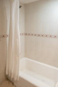 een wit bad met een douchegordijn in de badkamer bij Hotel San Francisco Centro Histórico in Mexico-Stad