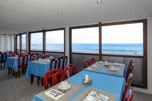 a dining room with tables and chairs and the ocean at Aparthotel Barracuda in Ponta Delgada