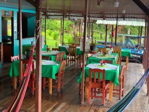 a dining room with green tables and chairs at All Rankins Eco-Lodge in Tortuguero