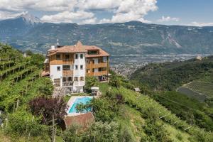 a house on a hill with a swimming pool and mountains at Aparthotel Abiná Lana Höhe in Lana