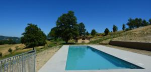 a swimming pool in a hill with a house at Agriturismo Le Case in Pietralunga