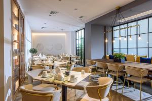 un restaurante con mesas, sillas y ventanas en DOM Boutique Hotel, en Heraclión