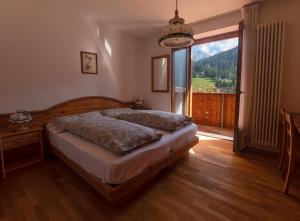 a bedroom with a bed and a large window at Dolomiti Hotel Cozzio in Madonna di Campiglio