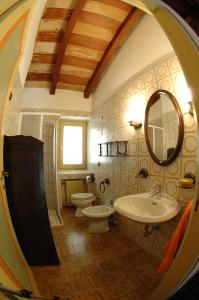 y baño con 2 aseos, lavamanos y espejo. en Mirabilia, en Adrara San Rocco