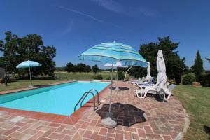 a swimming pool with two umbrellas and two lawn chairs and a swimming pool at Il Viaggiolo in Foiano della Chiana