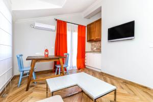 a living room with a table and chairs and a television at Apartments Vale Sorda in Bar