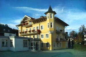 ein großes gelbes Gebäude mit einem Turm darüber in der Unterkunft Hotel Das Schlössl in Bad Tölz