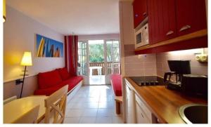 cocina y sala de estar con sofá rojo en Moliets Plage Appartement pour 4 Piscine proche Plage et Commerces, en Moliets-et-Maa
