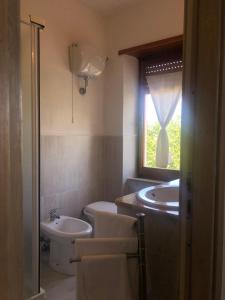 a bathroom with a sink and a toilet and a window at Su Poeta in Budoni +19 photos