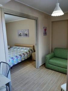 a bedroom with a bed and a green chair at La CampanellaLaura in Acireale