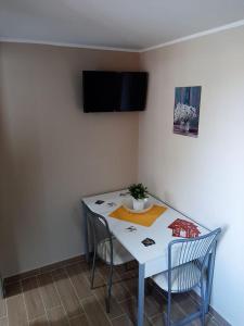 a dining room table with two chairs and a tv on the wall at La CampanellaLaura in Acireale