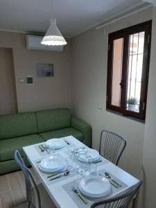 uma mesa com pratos e copos com um sofá verde em La CampanellaLaura em Acireale