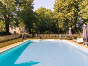 una piscina con due sedie a sdraio e ombrelloni di Cottage in Chaleix near Forest & Lake a Chaleix