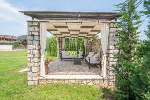 a stone pergola with a table and chairs in a yard at A Ponte Studios & Apartments in Sykia Chalkidikis