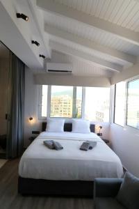 a bedroom with a large white bed with a large window at Triple A - Acropolis View in Psiri Athens - FREE Parking! in Athens