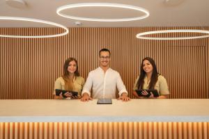 a man and two women standing behind a desk at Malibu Foz Hotel - La Maison Younan in Figueira da Foz