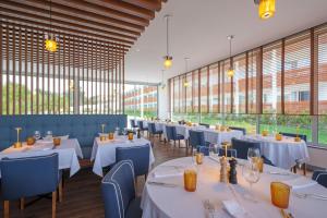 a dining room with white tables and blue chairs at Malibu Foz Hotel - La Maison Younan in Figueira da Foz
