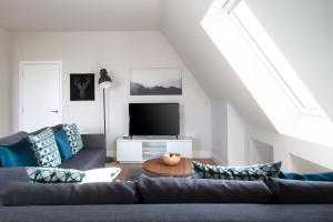 a living room with a couch and a tv at Hampden Apartments - The Richard in Windsor