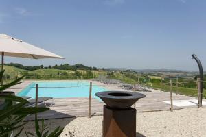 a swimming pool with a table and an umbrella at Agriturismo Unico Senso in Montottone