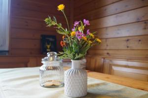 un jarrón blanco con flores en una mesa en Familien- und Sportappartements Wetzel, en Menzenschwand