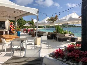 un patio con mesas de sillas y sombrillas junto al agua en Sapphire Beach Resort and Marina, en East End