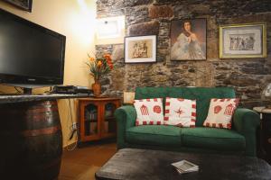a living room with a green couch and a tv at Raposeira Chloe T2 in Fajã da Ovelha