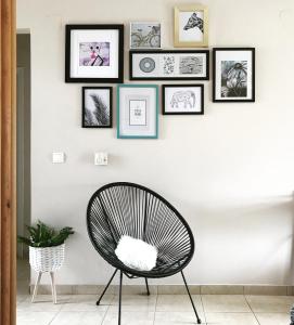 une chaise noire devant un mur blanc avec des photos encadrées dans l'établissement Sagini Boutique Hotel, à Loutra Edipsou