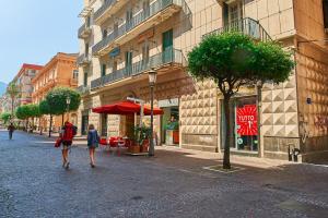 2 personnes marchant dans une rue avec un parapluie rouge dans l'établissement Casa sul Corso, à Salerne