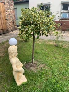 una estatua de un niño parado junto a un árbol en Pension Scheffler, en Potsdam