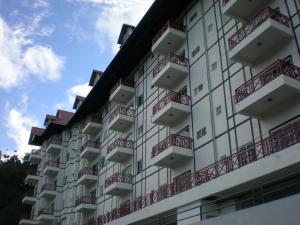 un edificio blanco con balcones rojos en CH Green Stay Resort Apartment, en Cameron Highlands