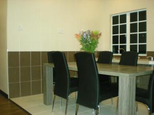 una mesa de comedor con sillas y un jarrón de flores en CH Green Stay Resort Apartment, en Cameron Highlands